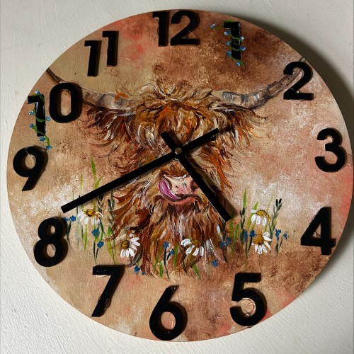 A handmade clock with a painting of a highland cow
